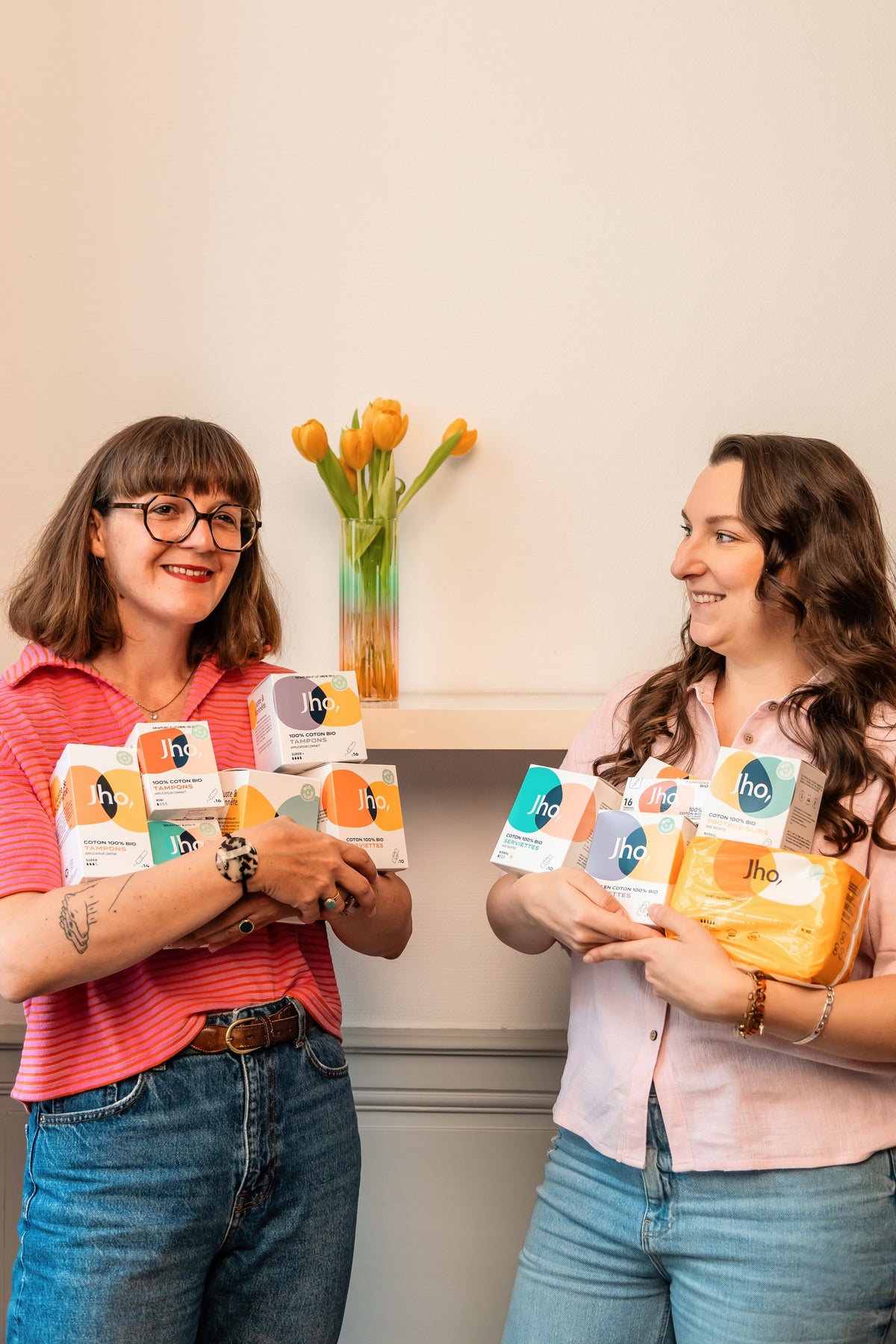 Deux femmes qui rient ensemble, les bras chargés de produits Jho