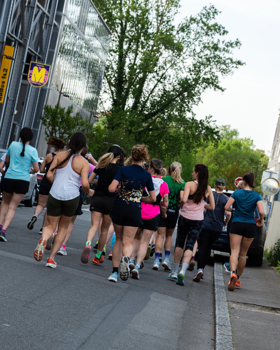 Des coureuses courent ensemble dans une rue bordée d'arbres